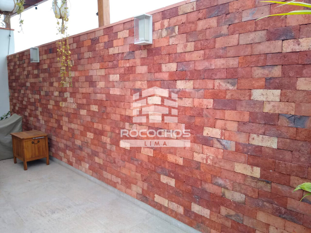 Enchape Natur en muro de terraza exterior con plantas y apliques de luz