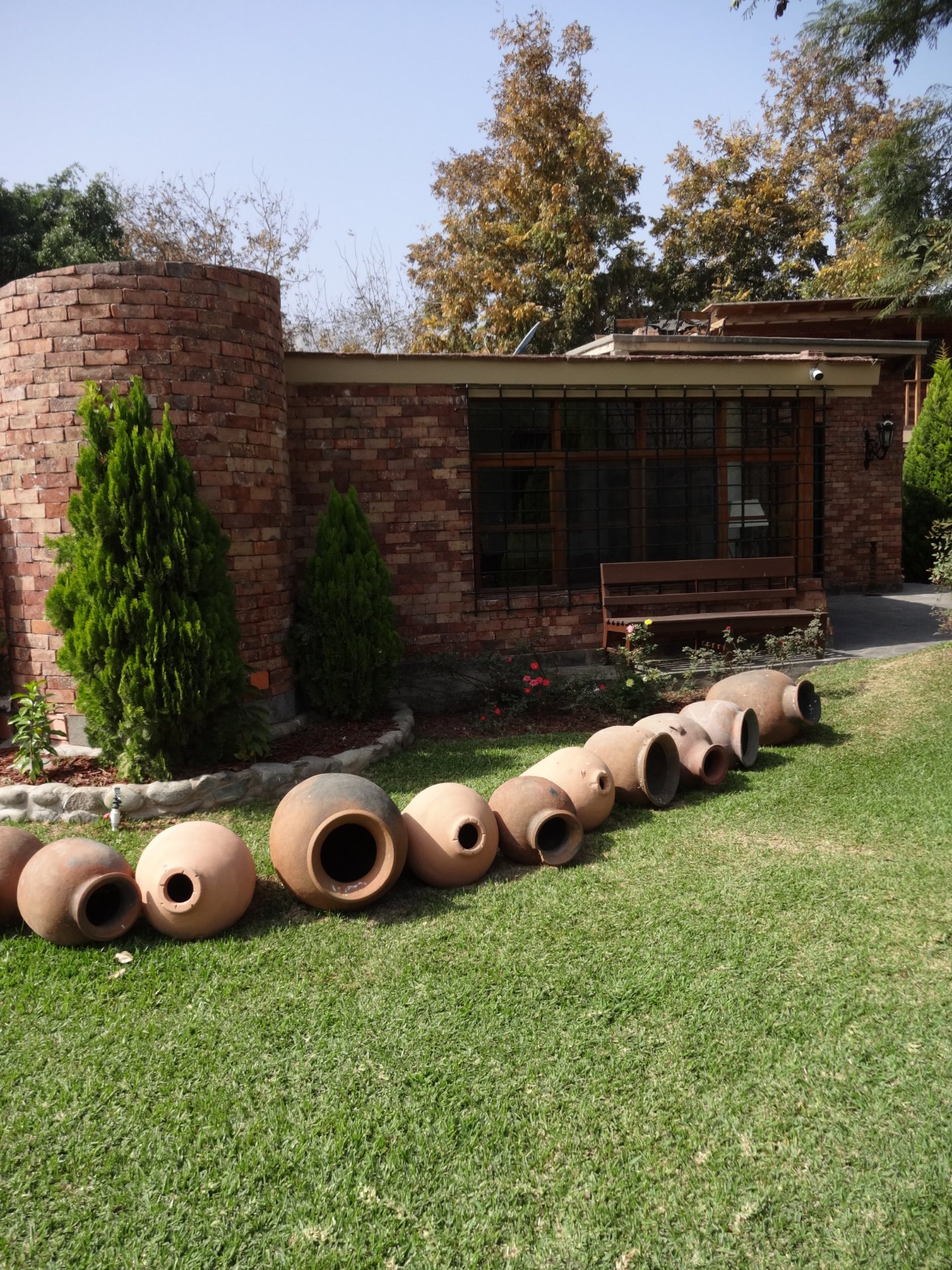 Enchape Antaño: casa de ladrillo con jardín y macetas de barro