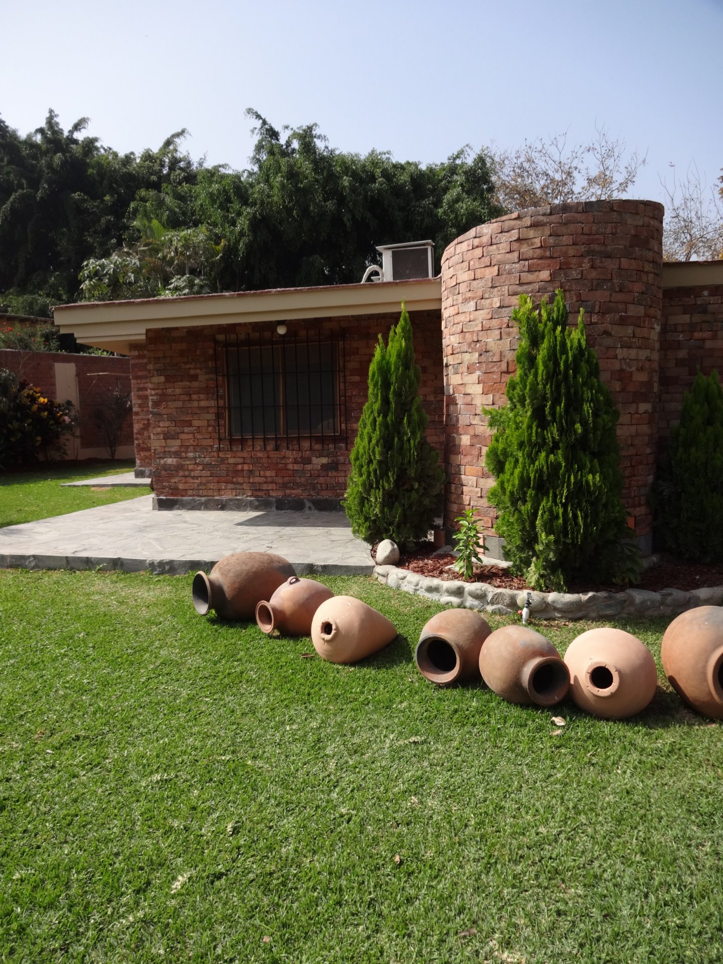 Enchape Antaño: casa de ladrillo con cipreses y césped