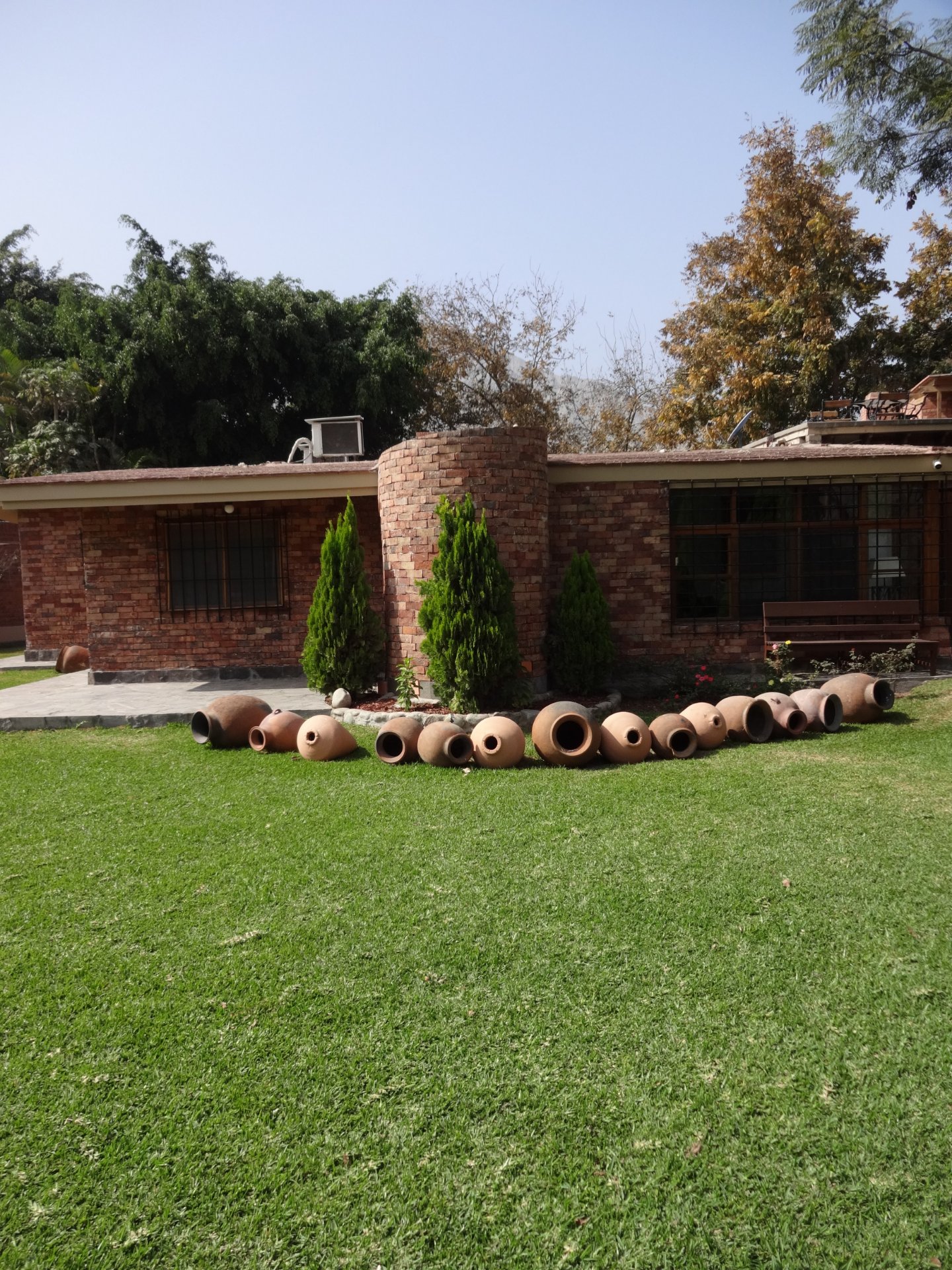 Enchape Antaño: casa de ladrillo con jardín de césped y macetas