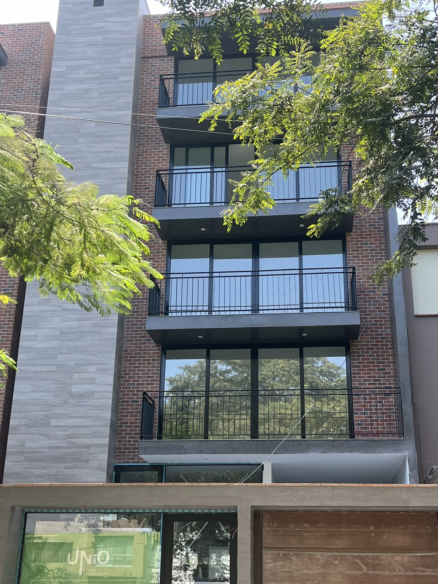 Enchape Hispano: edificio residencial moderno con ventanales y muro de ladrillo